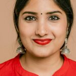 Charming close-up portrait of a South Asian woman with red lipstick and traditional jewelry.