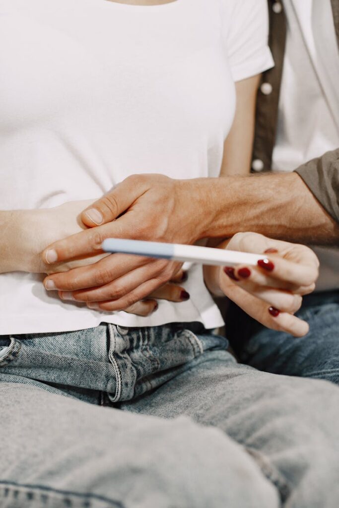 A couple joyfully embraces while holding a positive pregnancy test at home.