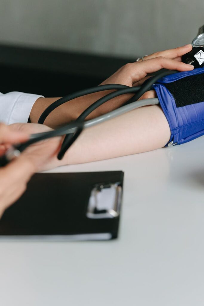 A healthcare worker uses a sphygmomanometer to check a patient's blood pressure in a medical office.